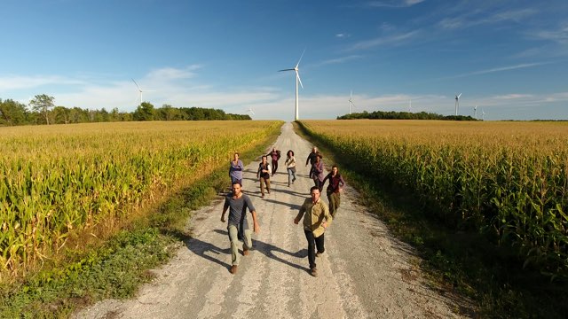 a group of dancers run down a path between cornfields